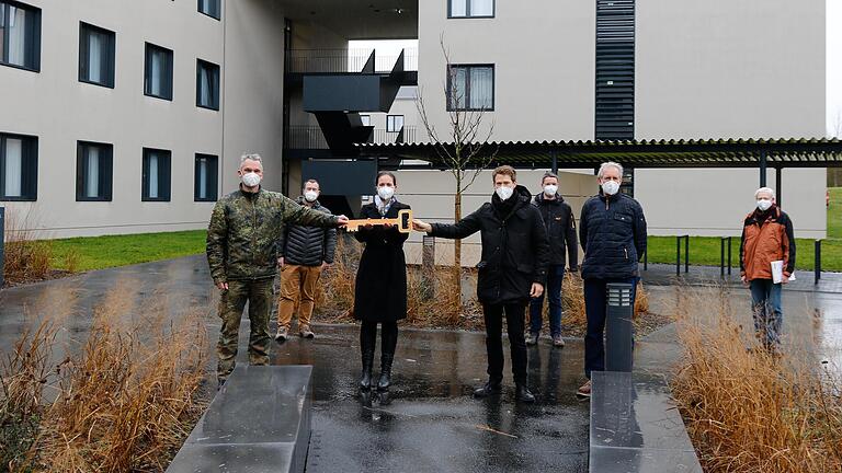 Übergabe des symbolischen Schlüssels (vordere Reihe): Alexander Sieg, Abteilungsleiter im staatlichen Hochbauamt Würzburg übergibt den Schlüssel zum neuen Unterkunftsgebäude (im Hintergrund) an die Objektmanagerin Sara Kauferstein vom Bundeswehr-Dienstleistungszentrum, die ihn ih-rerseits an den Infrastrukturoffizier der Balthasar-Neumann-Kaserne, Hauptmann Torben Fedder, weiterreicht. Die Übergabe des Gebäudes begleiten Steffen Gombert (Zweiter von links), Abteilungsleiter Dr. Christian Pötzinger und Bauleiter Georg Fuchs vom Hochbauamt (Fünfter und Sechster von links) sowie Michael Müller (rechts) von der neuen Eigentümerin, der Bundesanstalt für Immobilienaufgaben (BImA). Übergabe des symbolischen Schlüssels (vordere Reihe): Alexander Sieg, Abteilungsleiter im staatlichen Hochbauamt Würzburg übergibt den Schlüssel zum neuen Unterkunftsgebäude (im Hintergrund) an die Objektmanagerin Sara Kauferstein vom Bundeswehr-Dienstleistungszentrum, die ihn ih-rerseits an den Infrastrukturoffizier der Balthasar-Neumann-Kaserne, Hauptmann Torben Fedder, weiterreicht. Die Übergabe des Gebäudes begleiten Steffen Gombert (Zweiter von links), Abteilungsleiter Dr. Christian Pötzinger und Bauleiter Georg Fuchs vom Hochbauamt (Fünfter und Sechster von links) sowie Michael Müller (rechts) von der neuen Eigentümerin, der Bundesanstalt für Immobilienaufgaben (BImA).