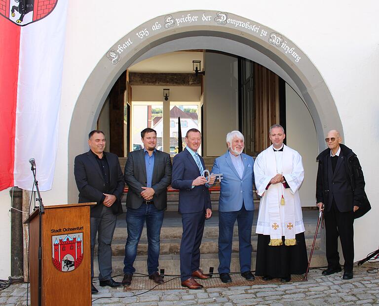 Schlüsselübergabe vor historischem Hintergrund. Architekt Thomas Schmucker, Historiker Georg Menig, Bürgermeister Peter Juks, Altbürgermeister und Archivar Peter Wesselowsky, Pfarrer Jochen Ley und Pfarrer Klaus Weber aus Hopferstadt.