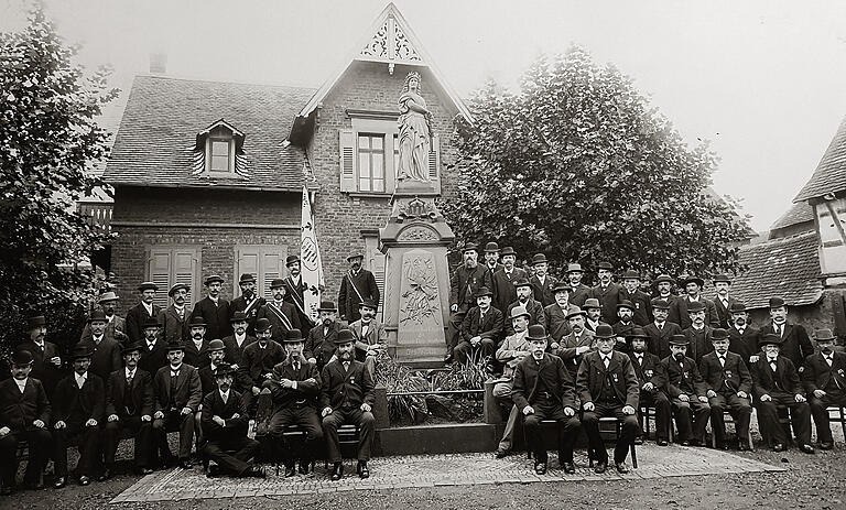 Das Bild zeigt die Feier zur Aufstellung des Gefallenen-Denkmals in Hanau-Steinheim im Jahr 1896. Die 'Germania'-Figur dieses Denkmals ist vom gleichen Bildhauer erschaffen worden, wie die Figur des Gerolzhöfer Denkmals, und ist mit dieser quasi identisch.