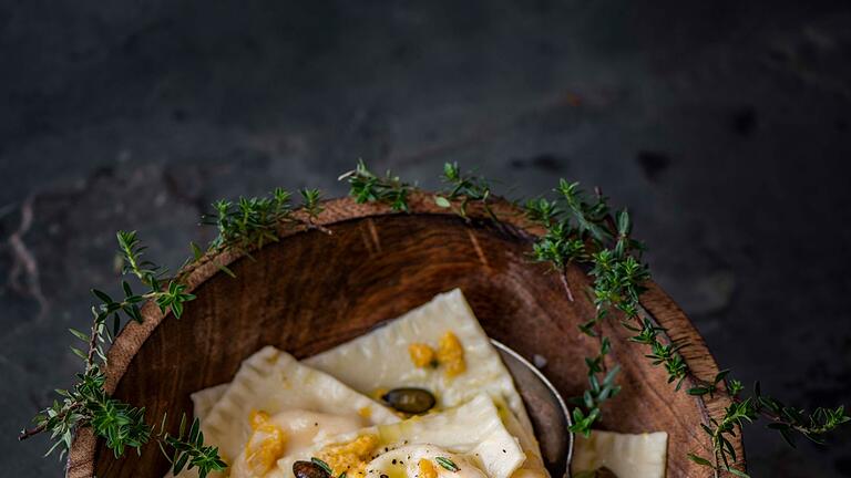 Kürbisravioli       -  Einen Teil der Kürbis-Ricotta-Mischung wird zum Servieren über die Ravioli verteilt und mit gerösteten Kürbiskernen und Parmesan getoppt.