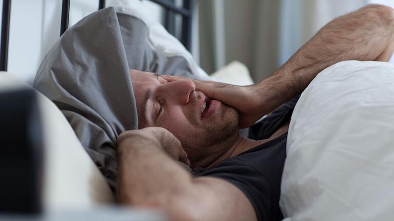 Ein Mann reibt sich die Augen im Bett - Unruhiger Schlaf wegen der Zeitumstellung? Bewegung und frische Luft sowie der Verzicht auf Mittagsschläfchen können hier helfen. Ein Mann reibt sich die Augen im Bett - Unruhiger Schlaf wegen der Zeitumstellung? Bewegung und frische Luft sowie der Verzicht auf Mittagsschläfchen können hier helfen.