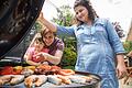 Eine Familie am Grill       -  Sicherer grillen: Damit keine potenziell krebserregende Stoffe entstehen, sollte Fleisch nicht zu lange direkt über der Glut garen.