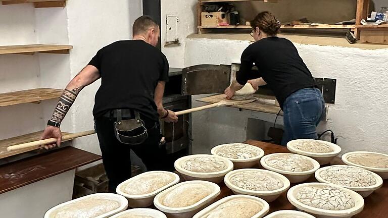 Christopher und Karin Böhm geben die Brote zum Backen in den Holzofen.