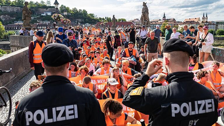 Bei über 30 Grad und Sonnenschein blockierte die Letzte Generation am Montagnachmittag die Alte Mainbrücke in Würzburg.