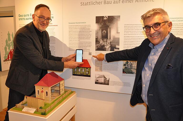 Gymnasiallehrer Jörg Thelenberg und Museumsleiter Bernd Brünner vor einer Museumstafel mit neuem QR-Code für die Übersetzung ins Englische. Gymnasiallehrer Jörg Thelenberg und Museumsleiter Bernd Brünner vor einer Museumstafel mit neuem QR-Code für die Übersetzung ins Englische.