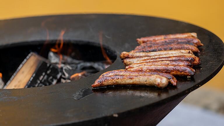 Am offenen Holzfeuer werden die Bratwürste gegrillt.