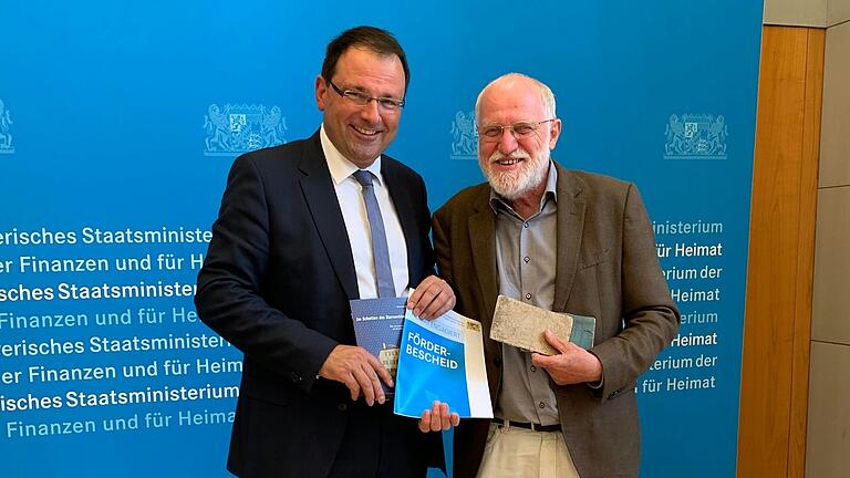 Reinhard Hüßner (rechts) nimmt in München einen Förderbescheid für den Förderverein ehemalige Synagoge von Finanzstaatssekretär Martin Schöffel (links) entgegen.