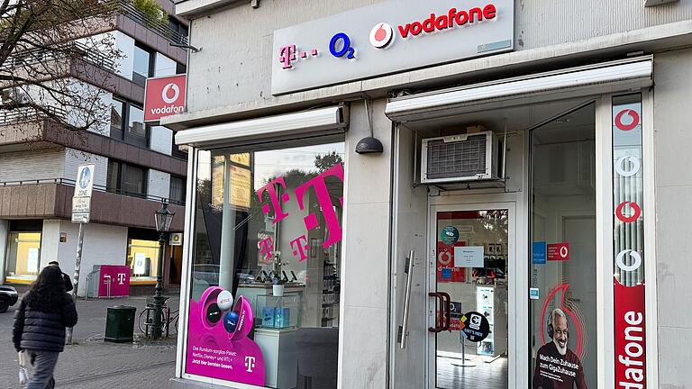 Mobilfunk-Shop       -  Eine Passantin geht in einer Fußgängerzone an einem Shop vorbei, der Mobilfunkverträge der drei etablierten deutschen Netzbetreiber Telekom, Telefónica O2 und Vodafone anbietet. Im Wettkampf um die Kundengunst bieten nun alle drei Anbieter Privatkunden reines 5G an, auch 5G SA genannt.