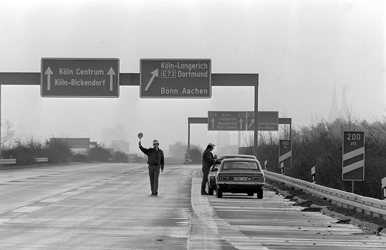Sonntagsfahrverbot: Am 25. November 1973 kontrollieren Polizisten bei Köln die wenigen Autos, die unterwegs sind. Haben die Fahrer wirklich alle eine Ausnahmebescheinigung? Sonntagsfahrverbot: Am 25. November 1973 kontrollieren Polizisten bei Köln die wenigen Autos, die unterwegs sind. Haben die Fahrer wirklich alle eine Ausnahmebescheinigung?