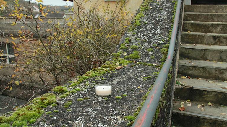 Auf der Betonbrüstung einer Treppe oberhalb der früheren Schule in Karlstadt-Laudenbach steht am Dienstag eine Kerze.