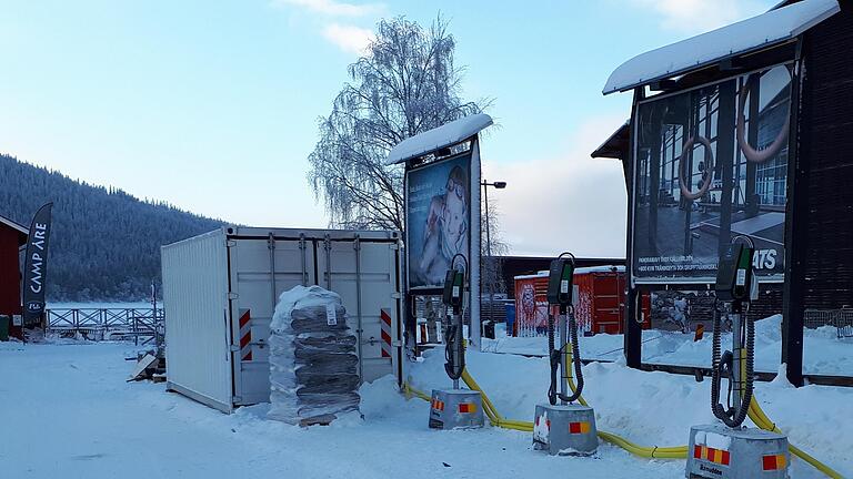 Ein Stromspeichersystem im weißen Container versorgt bei der Ski-WM Ladesäulen, die elektrisch betriebene Schneemobile aufladen.