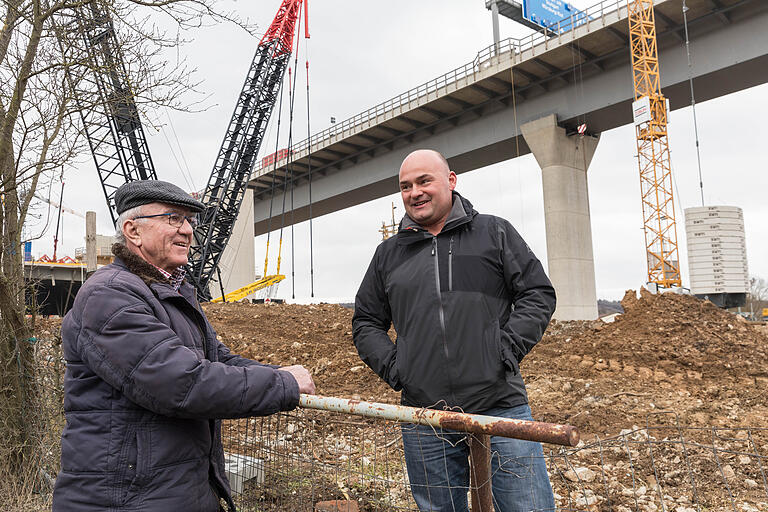 Reinhold Eck (links) trifft am Rand seines Gartengrundstückes Nachbar Michael Lang. Nur wenige Meter entfernt liegen die gestürzten Brückenpfeiler.&nbsp;