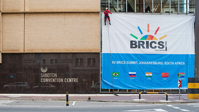 Vor 15. BRICS Gipfel - Vorbereitungen       -  Arbeiter bringen ein Banner für den 15. Brics-Gipfel, der am Dienstag startet, vor dem Sandton Convention Center an. Die Erwartungen an das Treffen sind nach Zwistigkeiten im Vorfeld gedämpft.