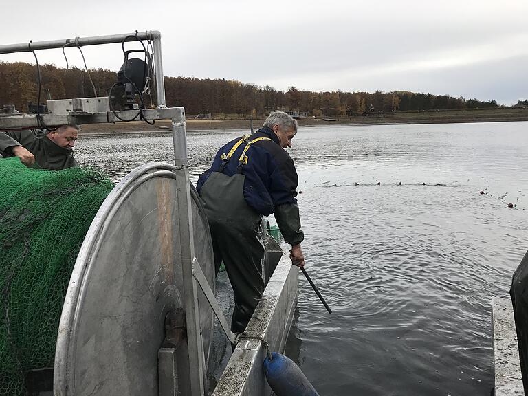 Peter Liebe schlägt mit einer Metallstange an die Bootswange. Der Lärm soll die Fische in den Fangsack treiben.