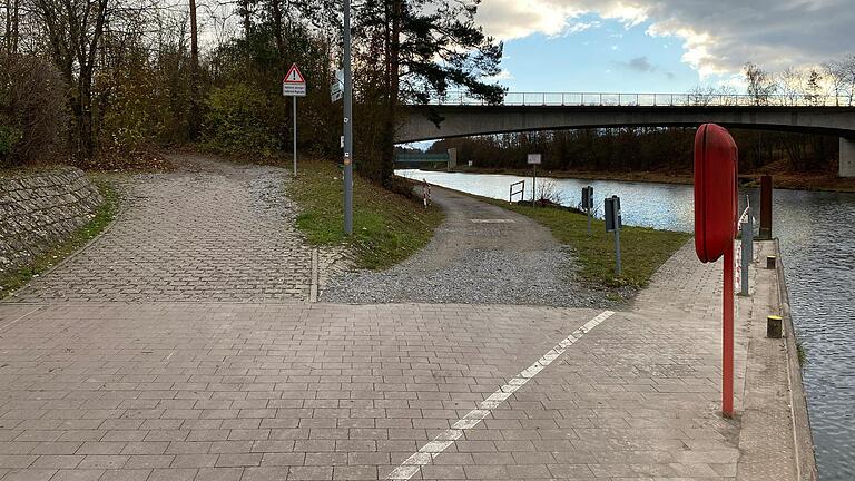 Von Nordheim kommend überqueren die Radfahrer die Brücke über den Mainkanal und biegen dann nach links ab auf die geschotterte Abfahrt, die sie hinunter an den Mainkanal führt. Auf dem steilen Pfad muss das Rad den Schildern zufolge geschoben werden. Von Nordheim kommend überqueren die Radfahrer die Brücke über den Mainkanal und biegen dann nach links ab auf die geschotterte Abfahrt, die sie hinunter an den Mainkanal führt. Auf dem steilen Pfad muss das Rad den Schildern zufolge geschoben werden.