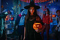 Halloween Costume Party: Gorgeous Seductive Witch Wearing Dress Holds Burning Pumpkin. Background: Beautiful Devil, Scary Death, Count Dracula, Zombie Dancing in the Decorated Room       -  Symbolbild: Halloween