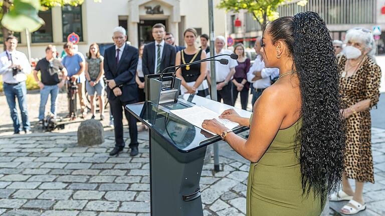 Die dritte Bürgermeisterin Judith Jörg (rechts im Hintergrund) hat am Dienstag am Paradeplatz in Würzburg zum Gedenken an den Genozid gemeinsam mit Serenada Schneeberger (am Pult), Vorstandsmitglied im Verband Deutscher Sinti und Roma, Landesverband Bayern e.V., Kränze zum Gedenken niedergelegt.