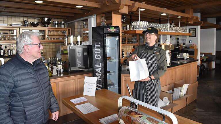 Werner Lawrenz (rechts) übergibt an einen Kunden, der vorher eine Bestellung aufgegeben hatte, im Höchberger Gasthaus Lamm ein frisch zubereitetes Menü.