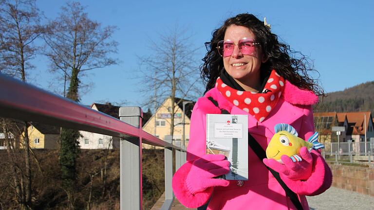 Mareen Kasper mit ihrem Märchenbuch und dem Fisch Gemo auf der Saalebrücke in Gemünden.