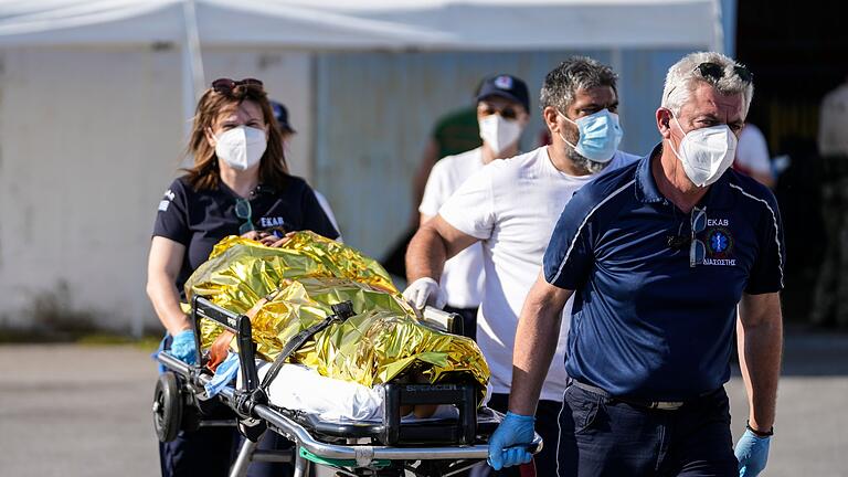 Bootsunglück in Griechenland - Sanitäter.jpeg       -  Sanitäter transportieren einen verletzten Überlebenden des Bootsunglücks zu einem Krankenwagen im Hafen der griechischen Stadt Kalamata.