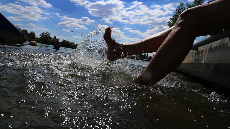 Sommerhitze - Kitzingen       -  Kitzingen: Eine Frau kühlt sich ihre Beine im Wasser des Mains.