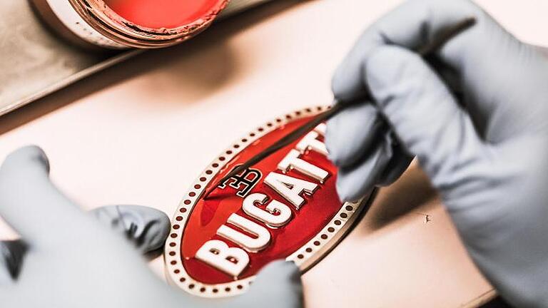 Logo, Hand anlegen: Ein Emblem für den Bugatti Chiron entsteht mit manueller Hilfe. Foto: Bugatti/dpa-tmn       -  Logo, Hand anlegen: Ein Emblem für den Bugatti Chiron entsteht mit manueller Hilfe.