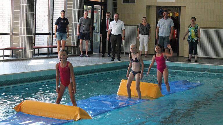 Eine neue Attraktion für junge Wasserratten bietet das Ostheimer Hallenbad: Stella, Leni und Anouk hatten sichtlich Spaß mit der Hindernislaufmatte. Mit ihnen freuten sich (am Beckenrand von links): Anna-Lena Klee (DLRG), Bademeister Volker Schmitt, Steffen Pfeiffer (Sparkasse), Bürgermeister Steffen Malzer, 3. Bürgermeisterin Jasmin Reuter, Matthias Leyh (DLRG) und 2. Bürgermeisterin Karina Werner.