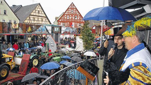 Kirchweih-Predigt mit Schirm, Charme und Murrmännern       -  (ast)   Trotz der Regentropfen war die Geiselwinder Kirchweih am Sonntag wieder ein Anziehungspunkt für viele Besucher aus der Umgebung. Die gute Laune der &bdquo;Murrmänner&ldquo;, so der Name der Kerwasburschen, schien damit nicht gestört, sie zogen mit einigen Motivwägen beim Umzug durch den Ort &ndash; mitsamt der Geiselwinder Musikanten. Wenigstens stand Prediger Bastian Rückel einigermaßen im Trockenen, als er hoch oben, von der Treppe der Bäckerei Müller am Marktplatz aus, die Predigt vortrug. Flankiert von Bürgermeister Ernst Nickel, der wieder in der Kluft der Geiselwinder Symbolfigur, dem schwedischen General Murrmann steckte, wusste Rückel so einiges aus dem Ortsgeschehen zu berichten. Die Kirchweih klingt am Montag zunächst mit dem Frühschoppen, später abends im Gasthaus Stern aus. Dort wird die Predigt noch einmal vorgetragen. Ein ausführlicher Bericht zur Kirchweih in Geislewind folgt in einer der nächsten Ausgaben der Zeitung.