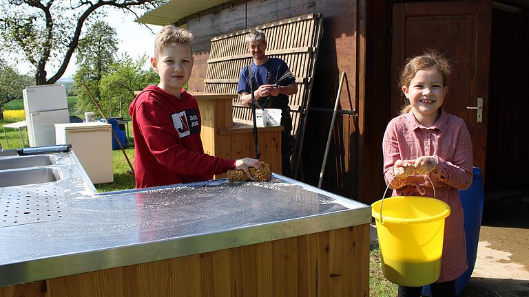 Beim Vatertagsfest in Rheinfeldshof arbeiten Kinder und Erwachsene zusammen. Julius (10)&nbsp; und Annabell Pfennig (8) putzen die Theke, Thomas Borst (Mitte) hilft ebenfalls.