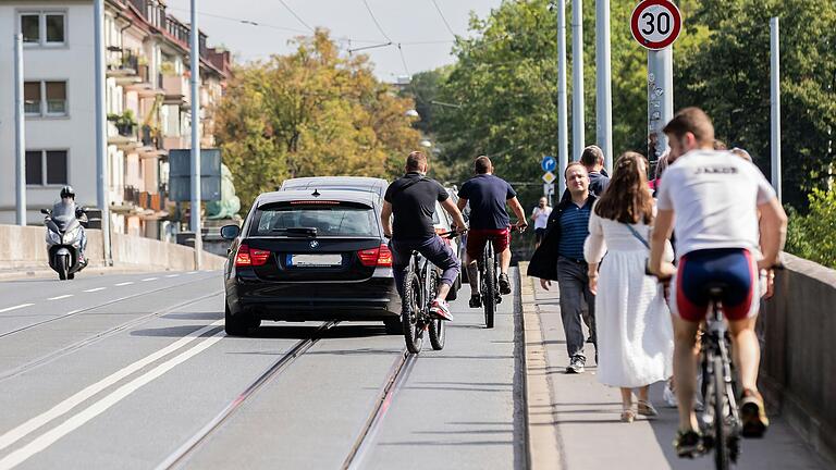 Auf der Würzburger Löwenbrücke gibt es keinen Radweg. Da sich Fahrradfahrende eine Spur mit den Bahngleisen und dem Autoverkehr teilen müssen, weichen manche unerlaubt auf den Gehsteig aus.