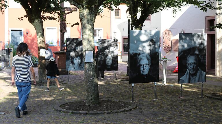 Die Ausstellung 'Begegnungen' des Fotografen Thomas Kohnle zeigt 16 Porträts, die auf acht großformatige Aluminiumplatten gezogen und zwischen den Linden am Lohrer Kirchplatz aufgehängt wurden.