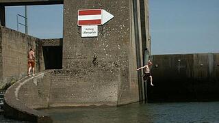 Riskantes Baden im Fluss       -  'Achtung Lebensgefahr': Schleusen oder Brücken ersetzen für Jugendliche oft den Sprungturm im Schwimmbad. Allerdings ist der Hechtsprung in den Fluss riskant, wenn unterhalb der Wasseroberfläche Treibgut schwebt. Zudem können sich an Schleusenwalzen und Brückenpfeilern gefährliche Strudel bilden.