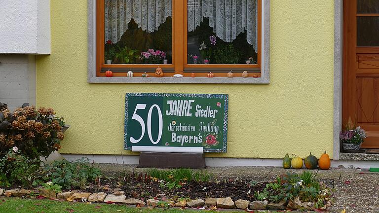 Am Haus von Erika und Toni Pöhnlein in der Franz-Schubert-Straße weist ein Schild auf „50 Jahre Siedler der schönsten Siedlung Bayerns“ hin.