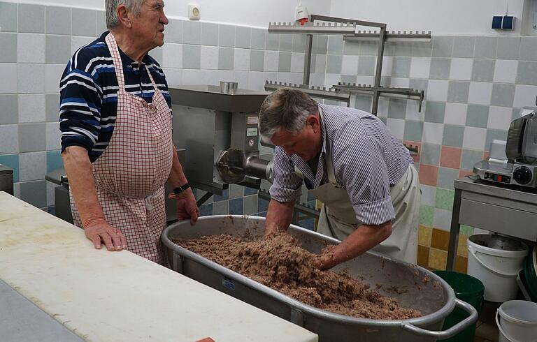 von links: Altbürgermeister Alfred Frank und Dieter Lauter kneten die gekochte Schweinescharte in die Wurstmasse von links: Altbürgermeister Alfred Frank und Dieter Lauter kneten die gekochte Schweinescharte in die Wurstmasse