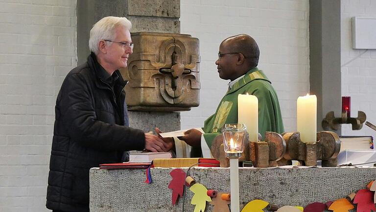 Heinz Zimmermann vom Vorstandsteam der KAB Erbshausen-Sulzwiesen (links) übergibt Father Dunstan Asiimwe die Spende über 600 Euro an dessen Waisenhausprojekt in Uganda.