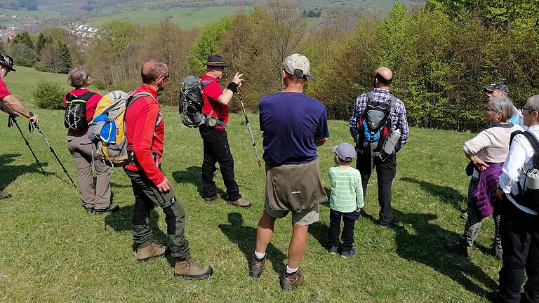 Kurzer Halt bei der Maiwanderung. Gegenüber auf dem Himmeldunkberg soll ein Gipfelkreuz aufgestellt werden. Initiator Christian Enders erläutert den interessierte Zuhörern einiges zu Aufstellungsort und Ausführung. Der Rhönklub Bischofsheim fungiert als Träger dieser Maßnahme, die bereits im Herbst 2022 abgeschlossen sein soll.