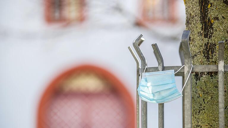 Masken überall, teils weggeworfen, teils verloren, teils bewusst als Dekoration eingesetzt. Mund- und Nasenschutz werden zum Sinnbild der Corona-Pandemie wie hier an einem Baum auf dem Haßfurter Marktplatz.