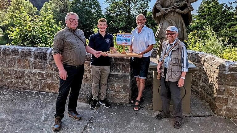 Die Übergabe des Floßes erfolgte traditionell auf der alten Saalebrücke. Martin Schmitt, Bürgermeister von Salz (Zweiter von rechts), überreichte das Floß an Sebastian Zwierlein (1. Vorsitzender Musikverein Hollstadt/Zweiter von links) und Georg Menninger (Bürgermeister von Hollstadt/links) mit den besten Wünschen für einen erfolgreichen Festverlauf. Begleitet wurde die Übergabe von Pfarrer Leo Brand (rechts).