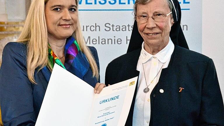 Melanie Huml (links), Staatsministerin für Gesundheit und Pflege, überreichte die Urkunde und eine Ehrennadel an Sr. Eberharda mit den Worten: &bdquo;Sie sind ein Engel.&ldquo;