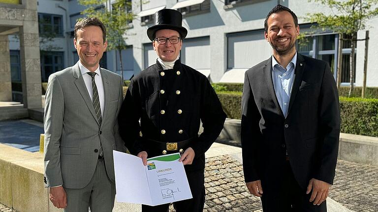 Da strahlen sie: Landrat Florian Töpper (von links) überreicht Kaminkehrermeister Bernhard Rath gemeinsam mit Wernecks Bürgermeister Sebastian Hauck die Urkunde 'Umwelt- und Klimapakt Bayern'.