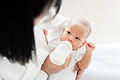Mother feeding asian baby with bottle of milk, banner copy space       -  Symbolbild: Mutter mit Baby