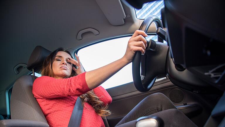 Erschöpfte Frau sitzt am Steuer ihres Autos       -  Müdigkeit? Schwindel? Bestimmte Medikament können die Fahrsicherheit beeinträchtigen.