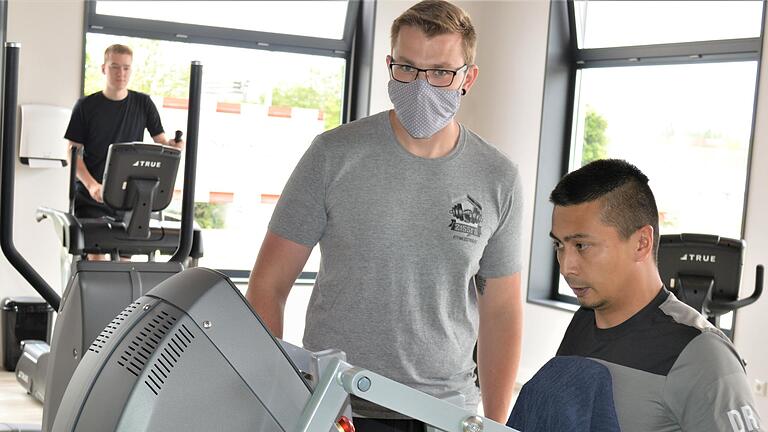 Die ersten Kunden sind da: Trainer Eik Döllner (mit Maske) weist einen jungen Mann in das moderne Trainingsgerät ein.