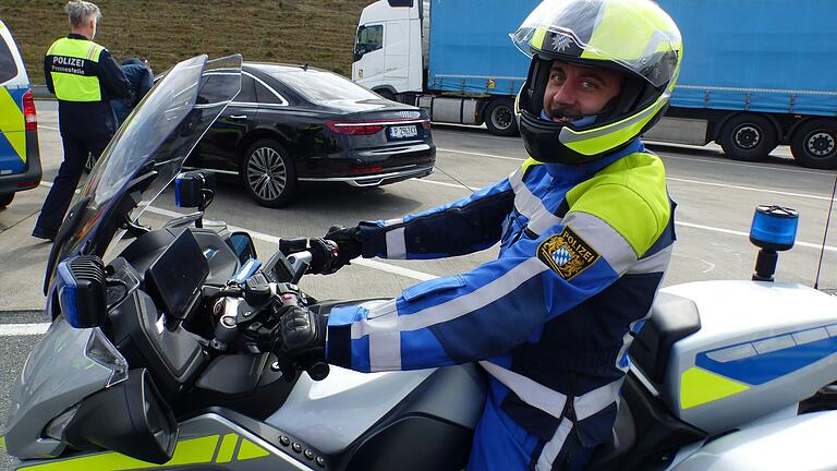 Der Fahrer eines Polizeimotorrads lotst ein Auto zum Kontrollort
