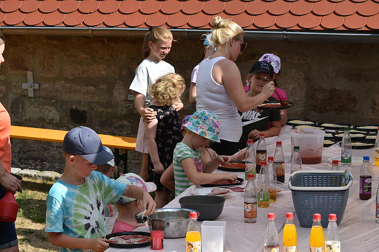 Das Bild zeigt einige Kinder beim Belegen ihrer Pizza.