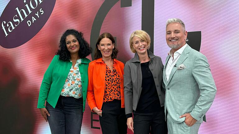 Eva Lutz (in orange) bei der Vorstellung ihrer neuen Kollektion bei QVC zusammen mit den beiden Models Tash (links) und Christine (rechts) und Moderator Frank Schäberle.