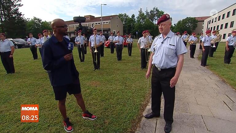 Reporter Yared Dibaba (links) besucht an Tag drei der Moma-Live-Schalte aus Veitshöchheim das&nbsp;Heeresmusikkorps. Rechts&nbsp;Oberstleutnant und Dirigent Roland Kahle.