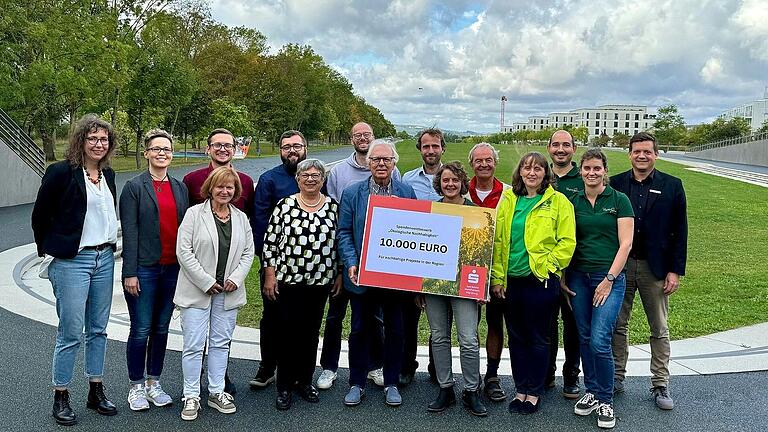 Daniela Mark, Fachreferentin Nachhaltigkeit (links) und Stefan Hebig, Abteilungsleiter Kommunikation (rechts) mit den Gewinnern der Nachhaltigkeitswettbewerbes der Sparkasse Mainfranken Würzburg