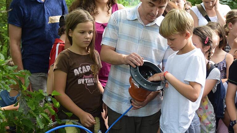 Strom direkt aus der Wasserströmung gewinnen       -  Aufmerksam begutachten die Kinder die Anspannung, die Wölbung und die Entspannung der Elastomer-Folie, die ihnen Fraunhofer-Mitarbeiter Thomas Gerlach erklärt.