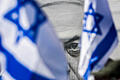 Bild des israelischen Premierministers Netanjahu ist hinter Fahnen       -  Das israelische Parlament hat den Weg für eine umstrittene Überarbeitung des Justizsystems von Ministerpräsident Benjamin Netanjahu frei gemacht.